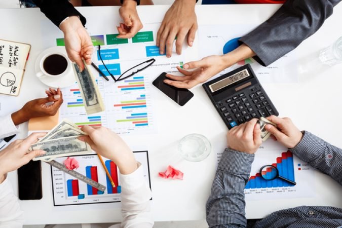 Picture of businessmen's hands on white table with documents, coffee and drafts